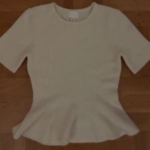 Ribbad vit topp med volang från H&M - Topp från HM, aldrig använt! Säljer då den inte sitter bra på mig☺️