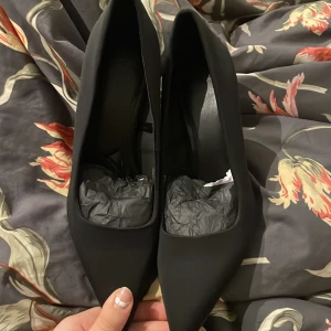 Svarta pumps med spetsig tå och hög klack - Säljer ett par stilrena svarta pumps från Ultimate med spetsig tå och hög smal klack. Köpte dem för 799 Skorna har en matt finish och är tillverkade i syntetmaterial. Perfekta för dig som vill ha en klassisk och elegant look. 