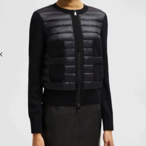 Svart quiltad cardigan jacka Moncler - Svart cardigan jacka från Moncler med quiltad front i dun och stickade ärmar. Jackan har rund hals, tvåvägsdragkedja och diskreta fickor framtill. Perfekt för dig som gillar en clean och stilren look med lite edge. Storlek M men sitter som Xs-S