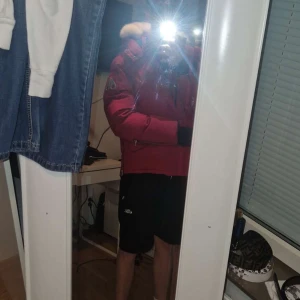 Röd dunjacka från Moose Knuckles - Säljer en röd dunjacka från Moose Knuckles med fet pälskrage, stora fickor och coola detaljer som grov dragkedja och tryckknappar. Jackan har svart innerfoder och broderad logga på insidan. Perfekt för kalla dagar när du vill sticka ut.