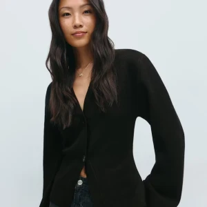 Svart kofta med knappar från Gina  - Stilren svart kofta från Gina med klassisk v-ringning och stora knappar framtill. Modellen har långärmade ärmar med breda muddar och är gjord i mjukt stickat material som känns skönt mot huden. Perfekt att matcha med jeans för en enkel och snygg look.