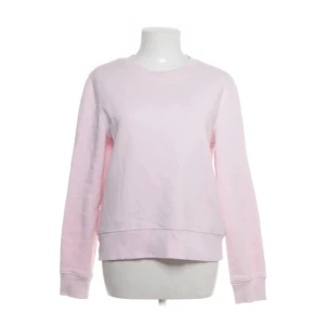 Ljusrosa sweatshirt - En enkel och snygg ljusrosa sweatshirt med rund hals och långa ärmar. Tröjan har ribbade muddar vid ärmslut och nederkant, perfekt för en chill och avslappnad stil. Mjuk bomullskänsla och klassisk passform.