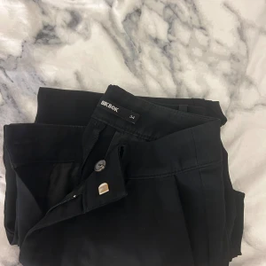 Svarta bootcut byxor från Bik Bok - Svarta bootcut-byxor från Bik Bok i storlek 34. Passar mig som är ca 160 cm. Gått sönder längst ner ( se 3 bilden)