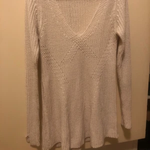 Beige stickad v-ringad tröja - Säljer en beige stickad tröja med v-ringad hals och långärmad design. Tröjan har en snygg strukturstickning som ger den extra karaktär och är perfekt för kyliga dagar. Passar dig som gillar en enkel men stilren look.