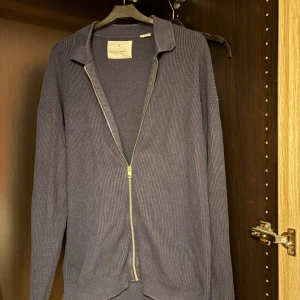 Mörkblå ribbad kofta från Jack & Jones - Snygg mörkblå ribbad kofta från Jack & Jones med dragkedja framtill och krage. Perfekt för lager-på-lager och chill dagar. Långärmad modell med mjukt stickat material som ger en skön känsla. Passar dig som gillar enkel och stilren look.