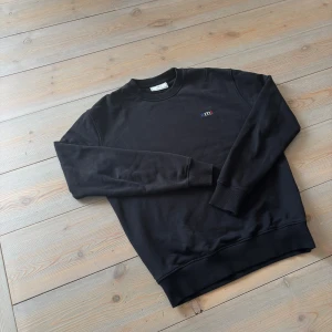 Svart sweatshirt från Ami Paris❤️ - Fransk toppkvalié - Svart Ami Paris tröja i strl M, jätteskön passform - perfekt för hösten. Tröjan har ett slitage - ändrar inte helhetsbilden, tröjan är fortfarande väldigt fin. Har även några små fläckar - går eventuellt att tvätta bort🧼Fransk premium tröja - snygg look🇫🇷Perfekt för vardagen🌟Passa på medans frakten är gratis🎁  