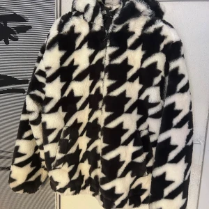 Svartvit pälsjacka från H&M Divided XS - Fluffig och oversized pälsjacka med huva från H&M Divided i storlek XS. Jackan har ett fett svartvitt rutigt mönster, dragkedja framtill och två sidofickor. Perfekt för dig som vill sticka ut med en bold look under höst och vinter.