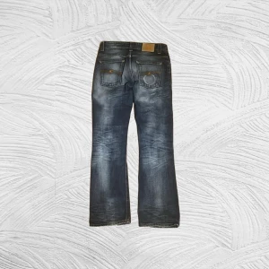 Nudie Jeans BootCutOla - Nudie Jeans BootCut Ola (W29 L31) Snygga jeans med en riktigt fin tvätt – naturliga slitningar och perfekt blå ton! Bootcut-passform med retro/2000-tals känsla. Mycket bra skick, inga hål eller fläckar.