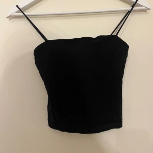 Svart linnetopp från Gina Tricot - Säljer en svart linnetopp från Gina Tricot i storlek XS. Toppen har tunna axelband och en enkel, stilren design som passar perfekt till jeans eller kjol. Materialet är mjukt och stretchigt för en bekväm passform.