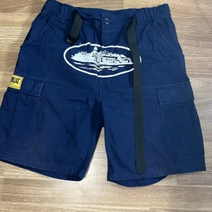 Mörkblå corteiz shorts  - Säljer ett par mörkblå cargo shorts från Corteiz. När jag köpte så tyckte jag inte dom va något snygga på just mig så dom har bara legat hemma och samlat damm. Kvitto letas fram om det vills. Använda kanske 2 gånger.