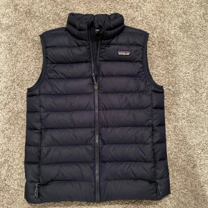 Patagonia Väst  - Säljer denna matinblåa Patagonia västen som är perfekt till hösten eller till våren. Nypris runt 1200kr och mitt pris är 699. Västen är i storlek 14 years men passar folk som har XS och är runt 160 cm. Hör av er vid minsta funderingar eller frågor. Priset kan diskuteras