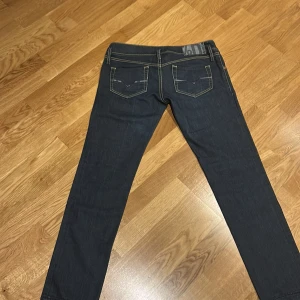 Diesel  mörkblå jeans - Säljer ett par mörkblå diesel jeans med snygga detaljer på bakfickorna, low waist. Jeansen har en ganska slim passform. Jag säljer dessa byxor för att de inte passar och knappt kommit till användning. 
