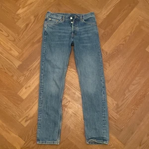 Weekday Pine Regular Tapered Jeans 28/32 - Blå klassiska jeans från Weekday i modellen Pine Regular Tapered. Jeansen har fem fickor, knappgylf och en snygg tapered passform som smalnar av nedtill. Tillverkade i bomull med en ljus tvätt och stilren look. Perfekta för dig som gillar enkel och clean stil. BRA SKICK!