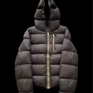 Rick Owens gimp jacka  - Svart pufferjacka från Rick Owens Strobe FW22 med stor huva och grov dragkedja framtill. Jackan har quiltad design, lång ärm och en extra bröstficka med dragkedja. Materialet är syntet och dun, perfekt för kalla dagar. Snygg och edgy look med oversized passform.