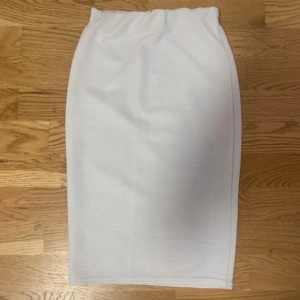 Vit rak pennkjol med resårmidja - Vit pennkjol med rak passform och resår i midjan. Kjolen är enkel och minimalistisk