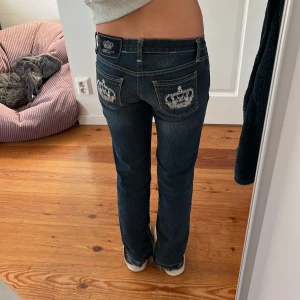 Rock & Republic x Victoria Beckham jeans - Snygga blå jeans från Rock & Republic i samarbete med Victoria Beckham. Modellen har raka ben, låg midja och coola broderade bakfickor med krona och blingdetaljer. Klassisk femficksdesign och silverfärgad knapp framtill. Perfekta för dig som gillar statement-jeans! De är storlek 29, innerbenslängd på 77cm och 37cm rakt över midjan💓Priset är inte hugget i sten!