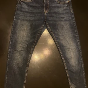 Blå jeans från LAB Industries - Snygga blå jeans från LAB Industries med klassisk femficksdesign och kontrastsömmar. Jeansen har en lätt tvättad look med slitningar på låren och knäna. Modellen är rak och passar perfekt till en avslappnad stil.