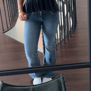 Blå bootcut jeans med normal passform - Säljer ett par klassiska blå jeans med bootcut-snitt och normal passform. Jeansen har fem fickor, dragkedja och knapp framtill. Perfekta för dig som gillar en tidlös look med lite utsvängda ben. Materialet är jeans i bomull.