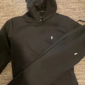 Svarta mjuk tracksuit  från Polo Ralph Lauren - Svarta tracksuit  från Polo Ralph Lauren med klassisk vit broderad logga på benet. Den är Beckväm han stayla hoody med jeans.jag säljer den där för att jag behöver pengar.