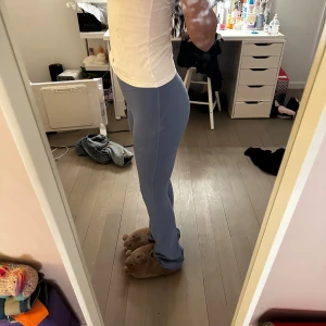 Blå tighta leggings i stretchigt material - Säljer ett par ljusblå leggings med hög midja och tight passform. De är gjorda i ett mjukt och stretchigt syntetmaterial som sitter skönt mot kroppen. Perfekta för dig som gillar en enkel och clean look. Från Lululemon men har en liten fläck på vänster ben ingen lapp kvar kan hitta orderbekräftelse om de behövs 