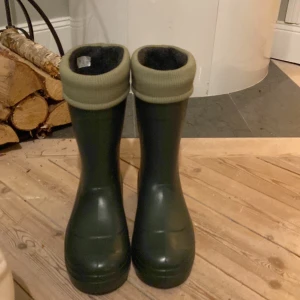 Mörkgröna stövlar från Camminare - Säljer ett helt nya mörkgröna stövlar från Camminare med grov sula och ribbad, ljusgrön kant upptill. Insidan är fodrad för extra värme och komfort. Lättviktstövlar, Perfekta för regniga dagar eller utomhusäventyr. Klassisk och robust design.storlek 38 men känns som 37. Hör av dig om du har frågor eller funderingar!