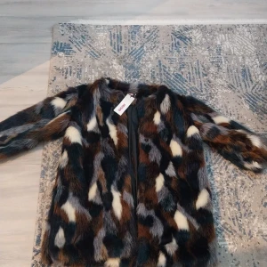 Flerfärgad pälsjacka från Indiska - Säljer en supercool pälsjacka från Indiska i storlek S. Jackan har ett mönster i svart, brun, beige och grå med långa ärmar och fluffig känsla. Perfekt statement-plagg för dig som vill sticka ut med stil.