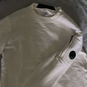 C.P company crewneck - Fin vit cp company crewneck om ni har fler frågor skicka kan gå ner i pris fråga om mer bilder  snöret som sitter på dragkedjan på armen är lite skadad, självklart äkta 