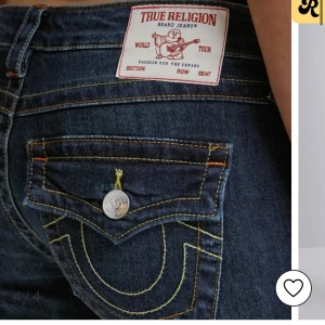 True Religion mörkblå bootcut jeans - Mörkblå jeans från True Religion med ikoniska kontrastsömmar och stora ficklock bak med silverfärgade knappar. Klassisk bootcut-modell med låg midja och snygg passform. Jeansen är tillverkade i denim och har tydliga detaljer som sticker ut.