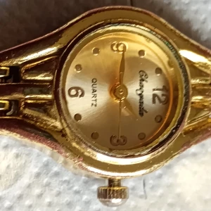 Guldfärgad Chaoquda damklocka - Snygg guldfärgad damklocka från Chaoquda med klassisk rund urtavla och länkarmband. Urtavlan har tydliga siffror och prickar, och klockan drivs av quartzverk. Baksidan är i rostfritt stål. Perfekt accessoar för dig som gillar stilrena detaljer.Nytt batteri behövs.