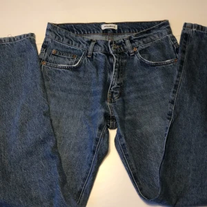 Blå jeans från Woodbird, storlek 28/32 - Snygga blå jeans från Woodbird i klassisk modell med fem fickor och bruna kontrastsömmar. Jeansen är tillverkade i bomull och har en rak passform som funkar till det mesta. Märkespatch i mockaimitation baktill och diskret etikett på insidan.