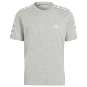 Grå Adidas t-shirt med vita ränder - Snygg grå t-shirt från Adidas med klassiska vita ränder längs axlarna och det ikoniska trefoil-loggan på bröstet. T-shirten är i mjuk bomull och har en normal passform med korta ärmar. Perfekt för en sportig och avslappnad stil.