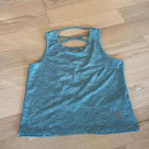 Turkos linnetopp från Born Primitive  - Säljer en turkosmelerad linnetopp från Born Primitive i storlek XS. Toppen har snygga snörningsdetaljer i ryggen och är ärmlös, perfekt för träning. Lite små i storleken, har två stycken om man vill köpa fler