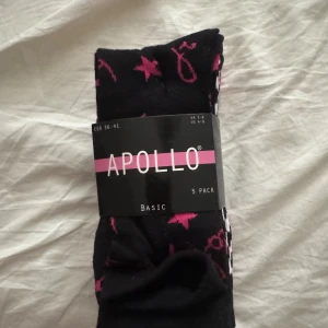 Färgglada mönstrade strumpor från Apollo - 5-pack strumpor från Apollo i olika färger som svart, grå, lila och rosa. Strumporna har coola mönster som stjärnor, hjärtan och rutor i kontrasterande färger. Perfekta för att liva upp vardagslooken och ge lite edge till outfiten.