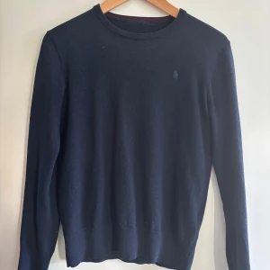 Mörkblå ulltröja från Ralph Lauren - Klassisk mörkblå tröja från Ralph Lauren i mjuk ull. Lite nopprig men tar självklart bor det vid köp. Lappen har tyvär lossnat men den är xs och kan försäkra om att den är äkta, köpt de butiken i NK