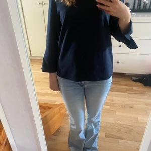 Mörkblå blus med öppning i ryggen från H&M - Säljer en stilren mörkblå blus från H&M i storlek S. Blusen har vida, trekvartsärmar och en snygg öppning i ryggen. Materialet är mjukt och känns som polyester. Perfekt för dig som gillar minimalistisk och clean look.