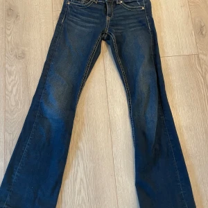 Blå bootcut jeans Gina Tricot 152 - Snygga blå jeans från Gina Tricot i storlek 152. Modellen har bootcut-ben och klassiska fickor med lock och knapp bak. Jeansen har kontrastsömmar och är tillverkade i ett mjukt denimtyg som sitter skönt hela dagen.