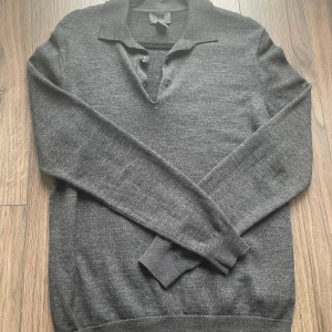 Mörkgrå merinoull polotröja H&M - En riktigt snygg mörkgrå stickad tröja från H&M. Tröjan är gjord av merinoull vilket gör den extremt skön att ha på sig. Tröjan är en Button-up med krage vilket blir extra skönt inför hösten. Bra skick,(7/10). Storlek S. Hör gärna av er vid några funderingar. Mvh Alvin.