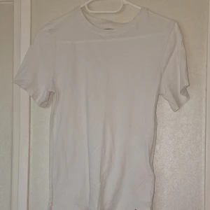 Vit t-shirt från Levi's i bomull - Klassisk vit t-shirt från Levi's med rund hals och korta ärmar. Tillverkad i mjuk bomull och har en liten röd Levi's-logga nertill. Perfekt basic-plagg att ha i garderoben. Den har någon liten noppra men inget som stör helhetsintrycket.