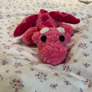 Virkad rosa drake  - Supersöt virkad drake i färgen rosa. Precis som många av mina andra figurer innehåller dessa drakar säkerhetsögon vilket inte rekommenderas för barn under 3 år.🩷