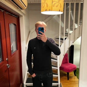 Svart ribbad tröja Calvin Klein Jeans - Svart ribbstickad tröja från Calvin Klein Jeans med diskret CK-logga på bröstet. Klassisk rund halsringning och långärmad modell. Perfekt för dig som gillar stilrena och enkla plagg med en snygg passform.