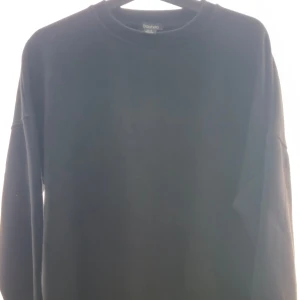Svart sweatshirt från Boohoo - En basic svart sweatshirt från Boohoo i storlek 36. Tröjan har rund halsringning, långa ärmar och en avslappnad passform. Perfekt för chill dagar eller när du vill ha en enkel och stilren look.