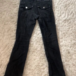 Svarta jeans från Gina Tricot , stl 42 - Svarta jeans från Gina Tricot i storlek 42. Utsvängda jeans och snygga bakfickor med lock och knapp. Jeansen har en mörk tvätt och är tillverkade i ett mjukt denimtyg. Perfekta för dig som gillar en enkel och stilren look.