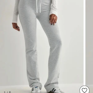 Grå mjukisbyxor med snörning - Snygga ljusgrå mjukisbyxor med bootcut-snitt och dragsko i midjan. Byxorna är tillverkade i mjuk bomullsmix och har en relaxed passform. Perfekta för chill dagar eller när du vill vara bekväm men ändå se fräsch ut.