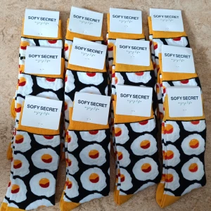 Strumpor med äggmönster - Färgglada strumpor från Sofy Secret med ett lekfullt mönster av stekta ägg på svart bakgrund. tillverkade i mjuk bomullsmix. Storlek: 41-46. Fina snygga strumpor. Priset gäller ENDAST för 1 par