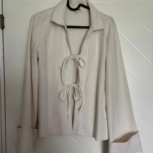 Tröja från Djerf Avenue - Tröja från Djerf Avenue i storlek S. Blusen har långa vida ärmar, krage och två snygga knytningar framtill. Använd fåtal gånger. 