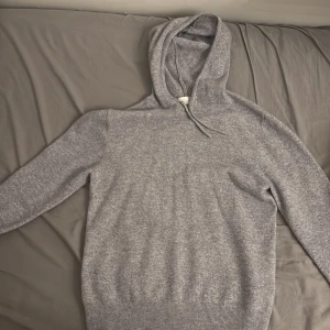 Grå kashmirhoodie från Sayless - Mysig grå hoodie från Sayless i mjuk kashmirblandning. Klassisk modell med huva och dragsko, ribbade muddar och lång ärm. Perfekt för dig som gillar stilren och enkel design med lyxig känsla. Det står att storleken är S men den har krympt så skulle säga xs. Passar nog dig runt 170