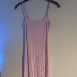 Ljusrosa långklänning från Amisu - En enkel och stilren ljusrosa långklänning från Amisu med smala axelband och rak passform. Klänningen är ärmlös och tillverkad i ett mjukt, stretchigt material som känns bekvämt mot huden. Perfekt för varma dagar eller när du vill ha en clean look. Denna klänningen ligger ute på Vinted oxå!