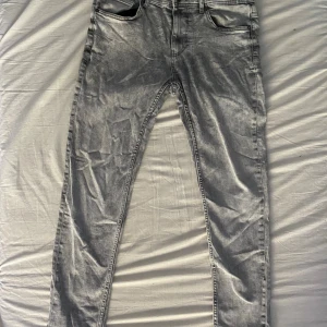 Grå skinny jeans med tvättad look - Snygga grå jeans med tvättad effekt och smal passform. Klassisk femficksmodell med dragkedjegylf och bälteshällor. Perfekta för dig som gillar en modern och stilren vibe. Pris kan diskuteras 