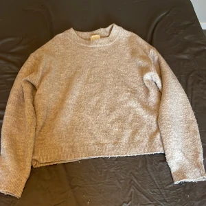 Beige stickad tröja från H&M - Mysig beige stickad tröja från H&M i storlek XS. Tröjan har en rund halsringning, ribbade muddar och är lite croppad i modellen. Perfekt för att få en chill och avslappnad look under höst och vinter. Den är använd några gånger och är lite nopprig.