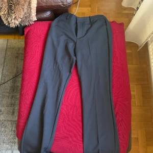 Svarta kostymbyxor från BikBok - Stilrena svarta kostymbyxor från BikBok i klassisk rak modell. Byxorna har hällor för bälte, dold dragkedja och knapp framtill. Perfekta för en clean och dressad look. Materialet känns mjukt och följsamt.